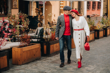 Portrait of a happy couple walking on the street in an autumn city. Stylish couple in retro style in autumn in the city