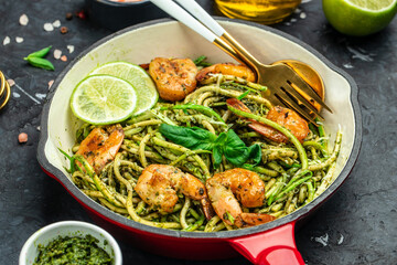 Zucchini pasta with pesto sauce and grilled shrimp in pan. Food recipe background. Close up