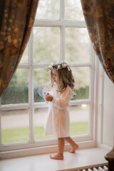 Little girl dressed up standing in diffused window light