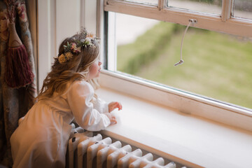 Little girl dressed up standing in diffused window light
