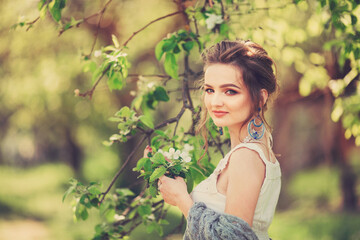 Beautiful blonde slender girl in a vintage look with a cape walks along the spring arch, sunset