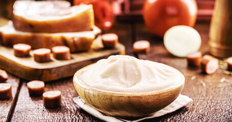 wooden bowl with lard, pork fat used as a brazilian cooking ingredient, bacon and pork sausage in the background