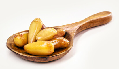 cooked pine nut seed in rustic wooden spoon, copyspace, isolated white background, brazilian restaurant food