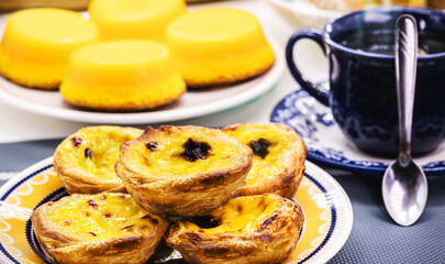 Traditional Portuguese dessert of pastel de nata, and bree de lis in the background, served with coffee, typical sweet made with eggs © RHJ