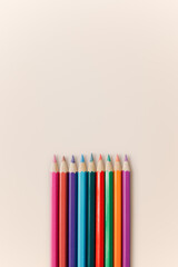 Colored pencils of various colors are arranged on a pastel background.