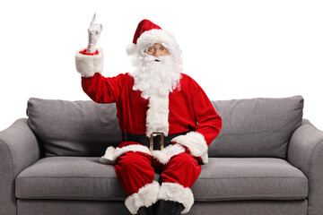 Santa claus sitting on a sofa and pointing up