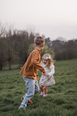 Brother and sister running together outdoors having fun, smiling and laughing