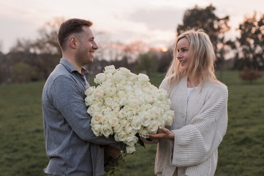 Young surprised couple family man woman in white clothes rest relax together boyfriend meet girlfriend gift give bouquet flowers at sunrise