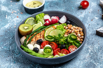 Buddha bowl dish with chicken fillet, avocado, asparagus, chickpeas, broccoli, radish, chicken, cucumber, tomatoes, olives, mozzarella. Detox and healthy superfoods concept, top view