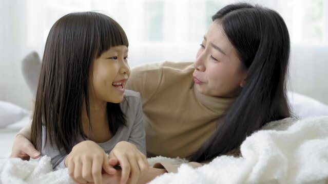Portrait of happy asian mother little daughter in the bedroom, laughing lying sleep in bed. Mommy and little girl spending time at home. Fun love family woman lifestyle together mother's day concept