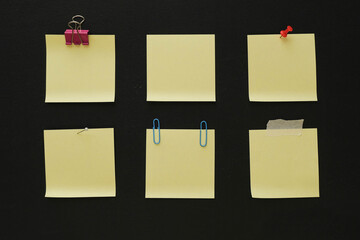 Collection of empty pinned yellow memo papers on a black background