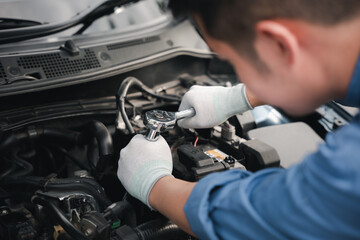 Service outdoor. Asian auto mechanic man working on car engine using wrench to repair and...