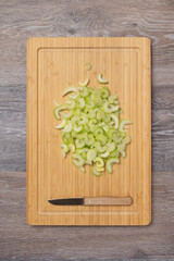 Stems of fresh juicy celery are sliced on a cutting board with copy space