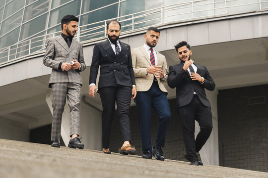 Business people outdoor meeting. A company of male businessmen in suits descend down the street stairs. Working break. Teamwork and brainstorming. Successful teamwork.