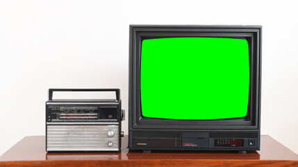 Vintage green screen tv and radio on wooden antique table, old house design. Old black vintage TV. East Germany GDR.