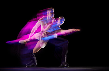 Portrait of artistic man and woman, figure skating athletes dancing isolated over black background...