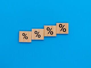 Wooden cubes with symbols of percentage, commission increase, insurance and savings on blue background.