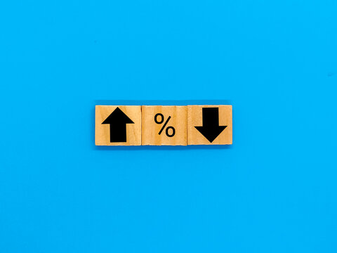 Percent symbols and arrows pointing up and down on them in a market, economy and price concept image.  Blue background.