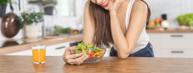 Diet, Dieting, smiling asian young woman, girl hand holding vegetables, green salad bowl on table at home, eat vegetarian food is low fat good healthy. Nutritionist weight loss for health person. - obrazy, fototapety, plakaty