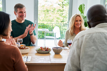 Two mature diverse couples gathered at the table having a good time