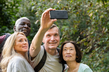 Fun diverse group of middle-aged friends taking a selfie in public park