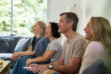 Diverse group of senior friends watching TV at linving room