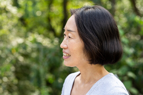 Side view shot of senior Asian-American woman standing outdoors - Powered by Adobe