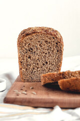 Sliced rye bread on a wooden board. Healthy bread with sunflower seeds and flax on a white background. Copy space.