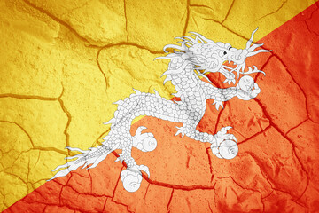 Flag of Bhutan. Bhutanese symbol. Flag on the background of dry cracked earth. Bhutanese flag with drought concept