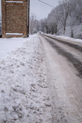 snow covered road in winter and old electric transformator building near road