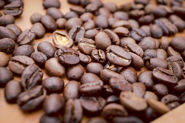 Roasted dark brown coffee beans on top of the wooden table, closeup  coffee seeds background