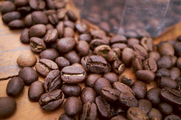 Roasted dark brown coffee beans on top of the wooden table, closeup  coffee seeds background