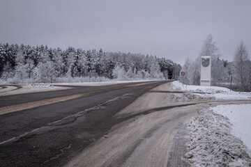 wet snow and mud covered asphalt road near Jelgava town, Latvia. Beautiful moody overcast winter...