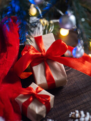 Christmas Gift boxes with red ribbons packed in kraft paper under the Christmas tree. Santa hat and garland , wooden table