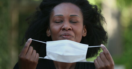 African woman taking off covid face mask feeling relief