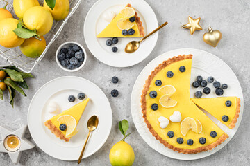 Traditional French lemon pie with blueberries on a white stone background.