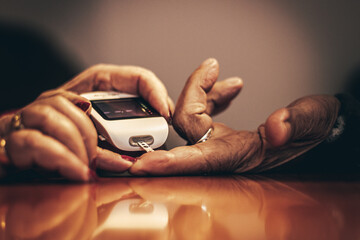 Crop elderly woman measuring blood sugar of husband with glucometer