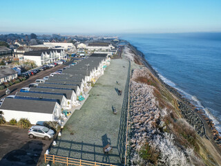 Obraz premium Aerial view of holiday chalets seen on the Suffolk coast during early winter. A couple can be seen out for an early stroll with the North Sea in view.