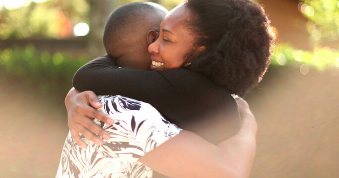 African couple embrace outside with lens-flare, romantic moment between two people