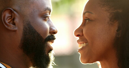 African coule foreheads together looking at each other and kissing with flare