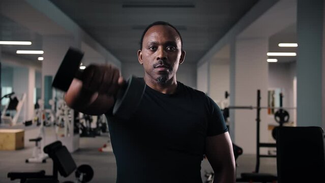 Black man workout with dumbbell training shoulders in gym.Bodybuilder training muscular doing dumbbell fly holding heavy dumbbells in hands.African American Fitness guy weight lifting.