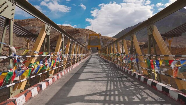 4K shot of Chicham bridge with Buddhist prayer flags fluttering in wind at Spiti Valley, India. Connects the two villages Chicham and Kibber. Highest suspension bridge of Asia. 4,145 meters above sea 