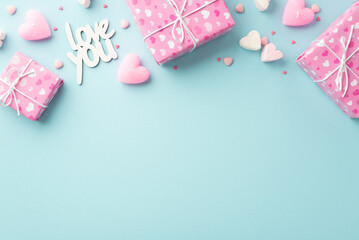 Valentine's Day concept. Top view photo of pink gift boxes in wrapping paper with heart pattern marshmallow candles inscription love you and sprinkles on isolated pastel blue background with copyspace
