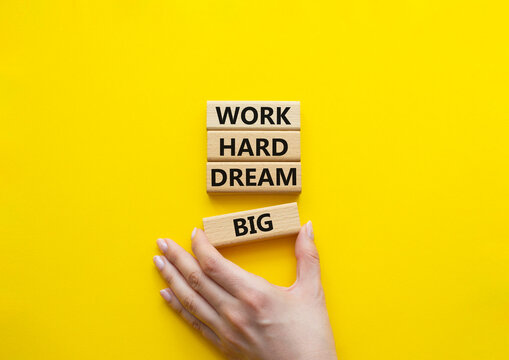 Work and dream symbol. Wooden blocks with words Work Hard Dream Big. Beautiful yellow background. Businessman hand. Business and Work Hard Dream Big concept. Copy space.