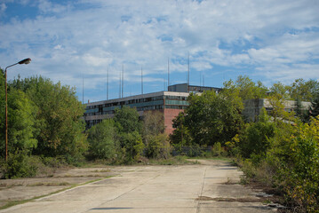 Fototapeta na wymiar Abandoned industrial building overgrown with trees
