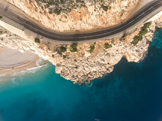 Aerial view of empty road between the mountains and a secluded beach