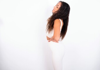 teen girl with curly hair wearing white sport set over white background got back pain