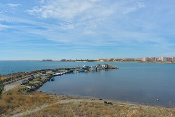 Beautiful sea view on a clear sunny day. You can see the pier with fishing boats and the city on the horizon