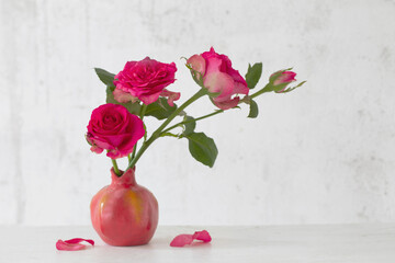  pink roses in pink vase on background old white wall