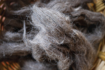 Extreme close-up horizontal photograph of gray wool fiber stacked ready to be spun, an image of gray wool bundled inside a basket.